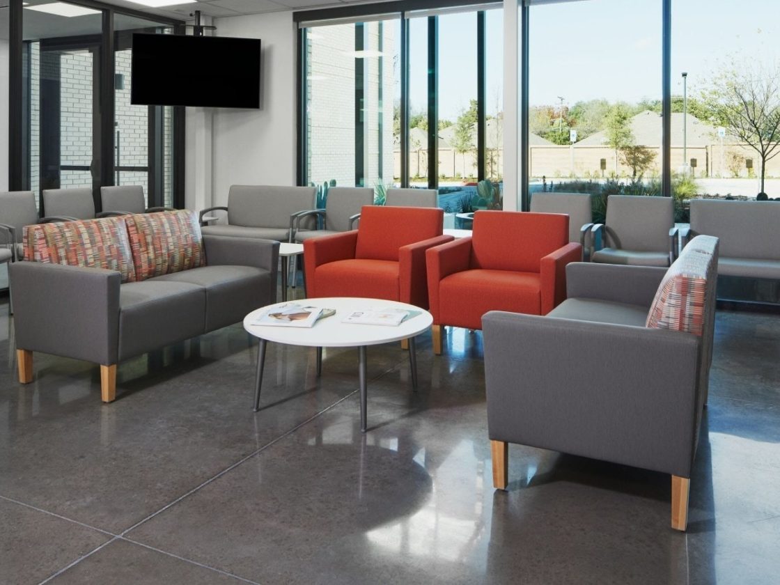 Lobby waiting area with Nemschoff Healthcare Waiting Area collection of grey couches, red chairs, white coffee tables, and grey outer-rim seating