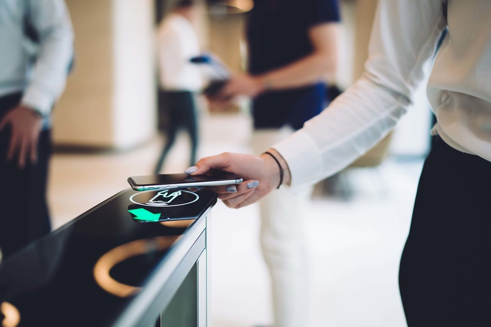 Close-up of a person using a smartphone to scan a digital access point, showcasing modern contactless entry technology in a sleek office environment.