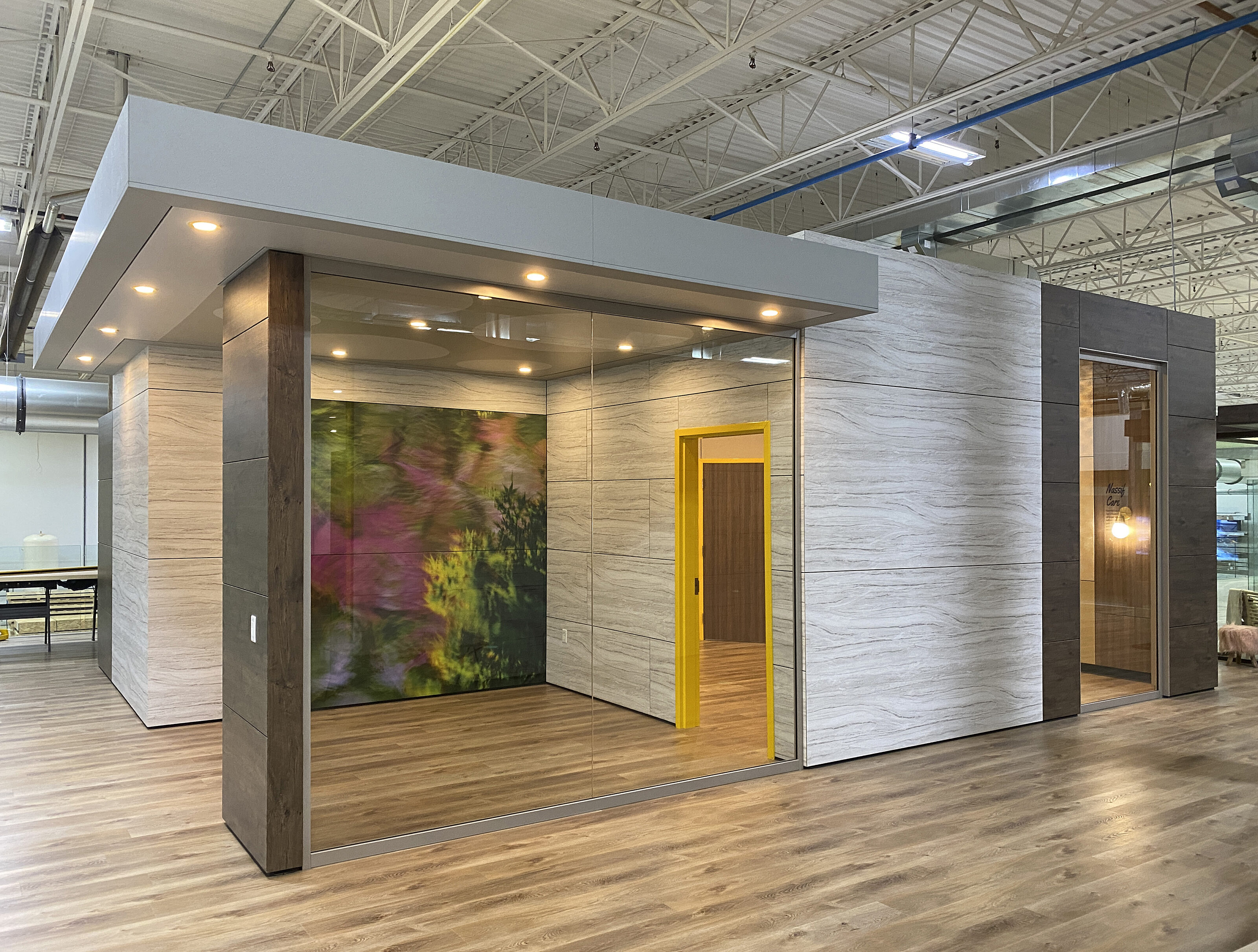 Modular office with Falkbuilt wood-pattern walls, glass panels, and a mural inside. It features recessed lighting in a bright industrial space.
