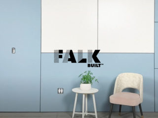 Falkbuilt wall system in light blue with a small round table holding a plant and a modern upholstered chair, demonstrating clean, modular design.