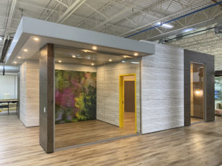 Modular office with Falkbuilt wood-pattern walls, glass panels, and a mural inside. It features recessed lighting in a bright industrial space.