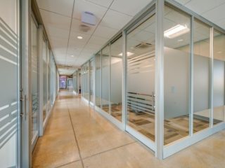 Office hallway with frosted glass Symbio walls, modern lighting, and polished concrete floors, creating a clean and professional workspace.