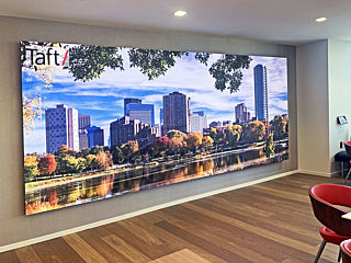 A vibrant digital display showcasing a city skyline and park, adding dynamic visual appeal to a office setting with sleek furniture and wood flooring.