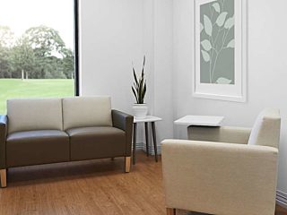 Patient consultation room with beige Nemschoff arm chair, Brown Brava Classic Multiple Seating, Nemschoff Palisade Mobile Table and Palisade Side Table.
