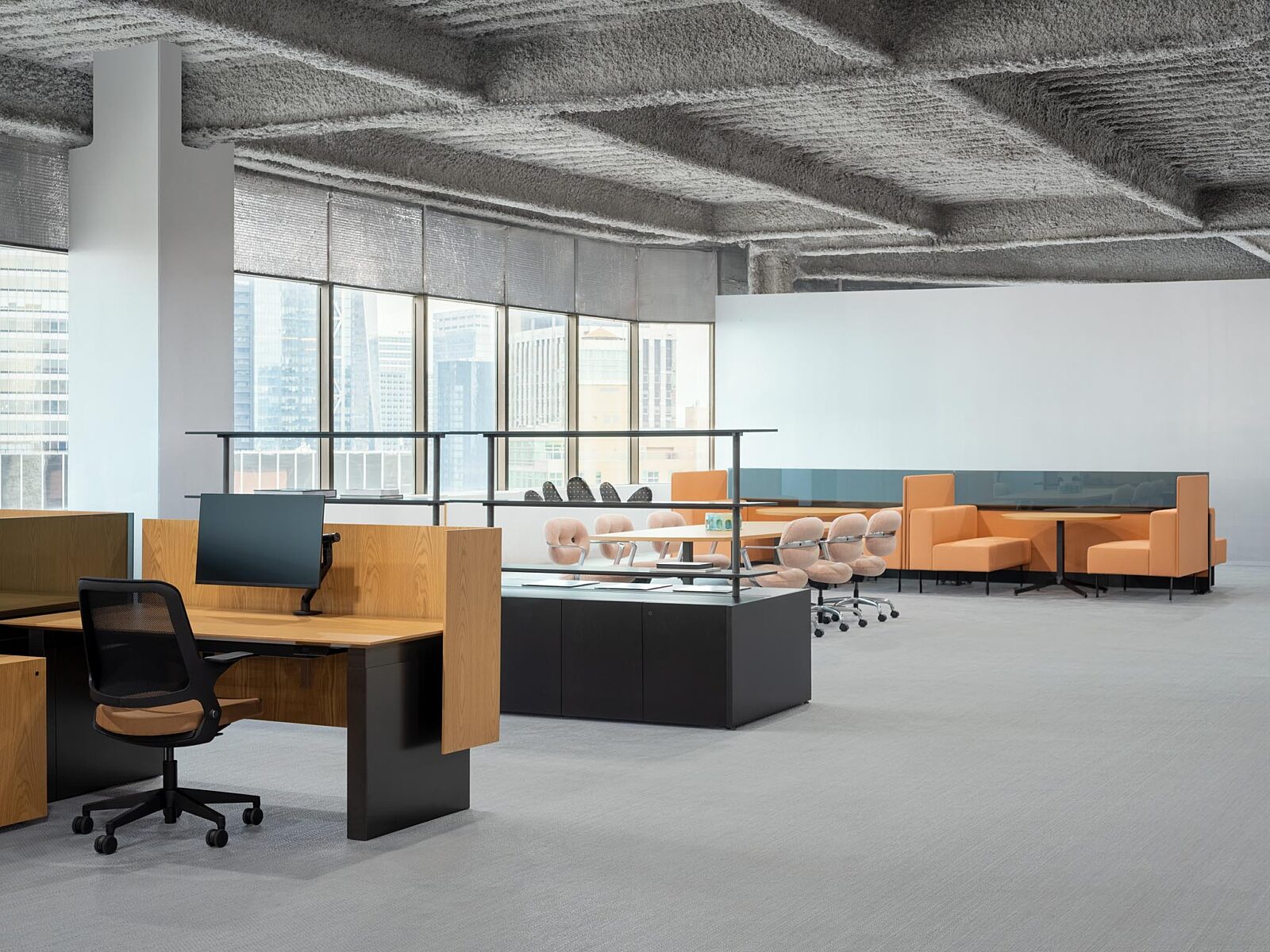 Open office with wood workstations, black storage, rolling chairs, and orange lounge seating.